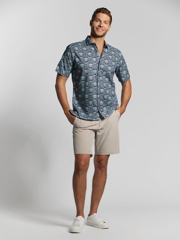 Blue palm-print short-sleeve shirt, beige shorts, and white sneakers.