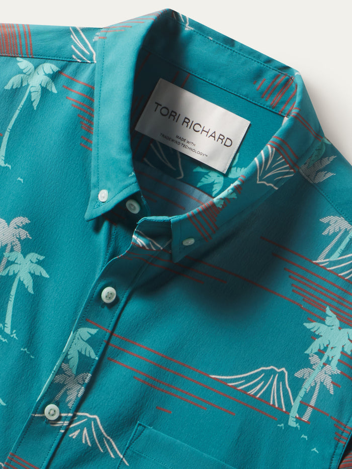 Teal shirt with white palm print, red accents, short sleeves; moisture-wicking fabric, front and detail views.