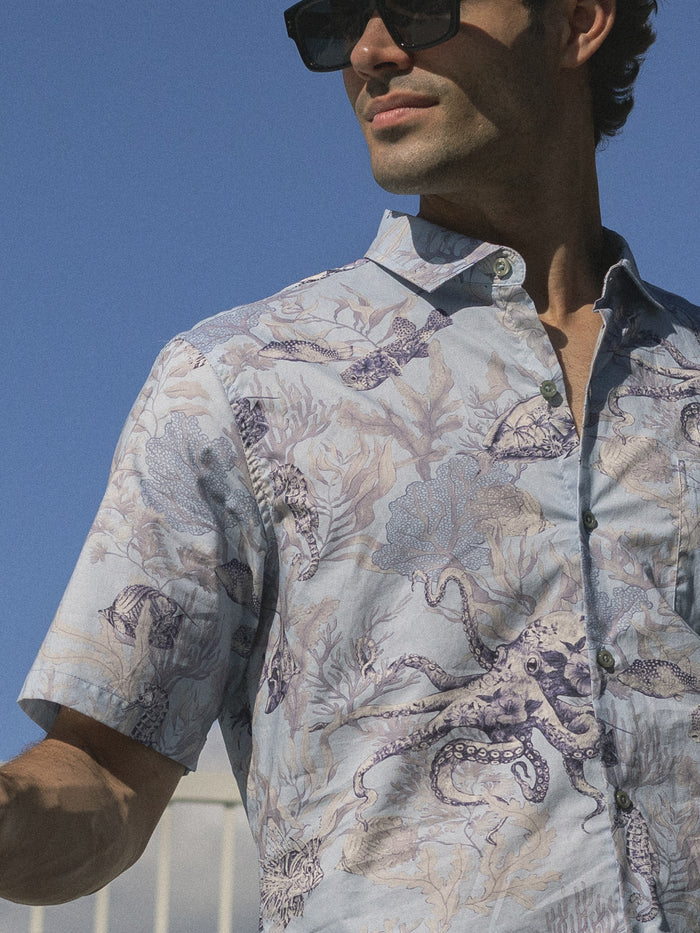 Light blue octopus and fish print Hawaiian lawn shir outdoor front view with man wearing sunglasses outside sunny day weather.