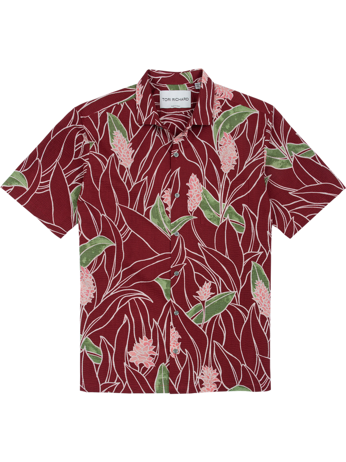 Red tropical floral-print short-sleeve cotton shirt with green leaves, flat lay front view.