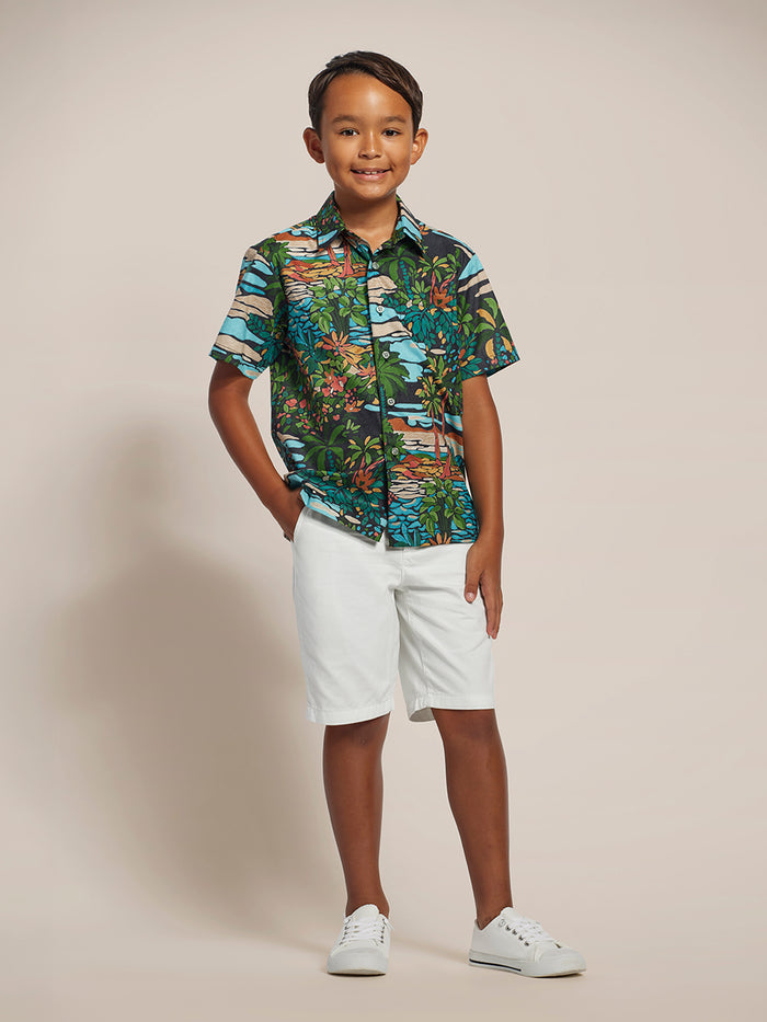 Boy in multicolor short-sleeve shirt, white shorts, and sneakers, full front view.