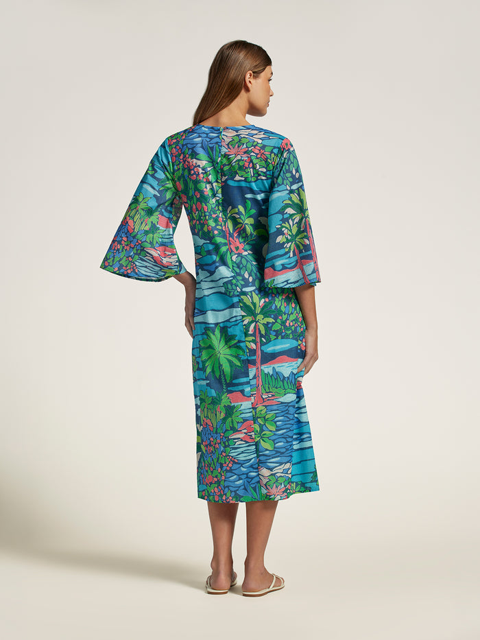 Opalescent tropical-print caftan, back view, model barefoot on plain background.