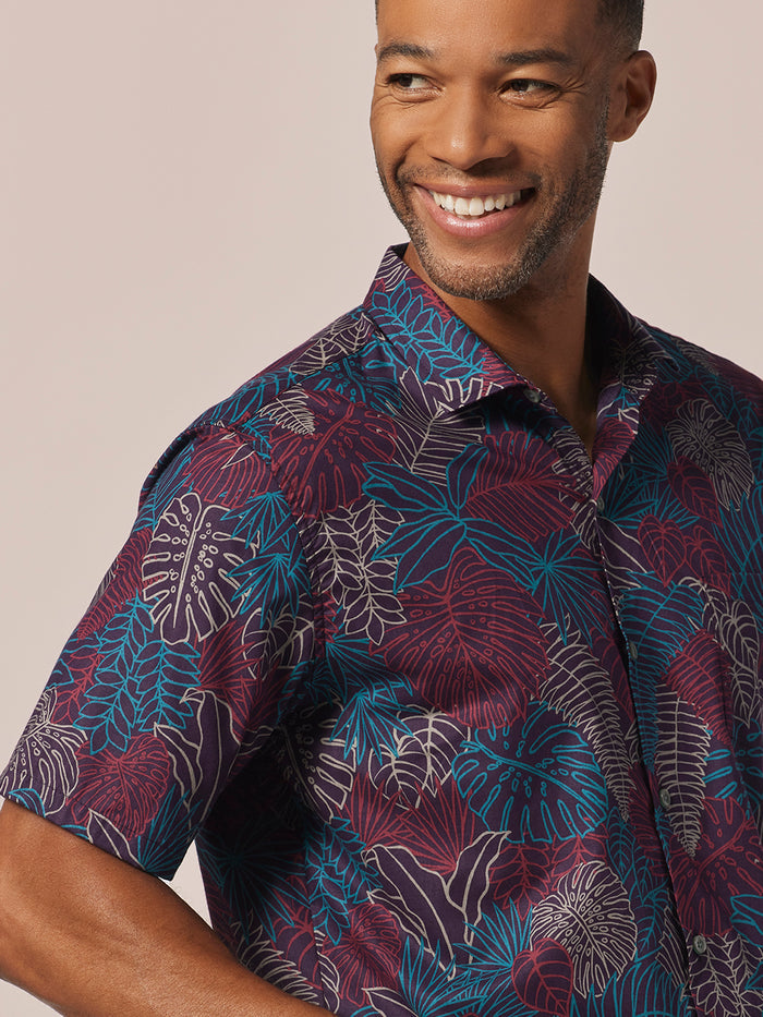 Purple short-sleeve shirt with blue and white tropical leaf print, front view.