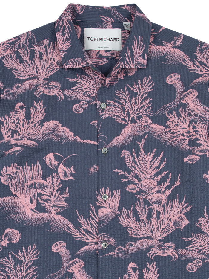 Navy shirt with pink coral and fish print, white buttons, front view.
