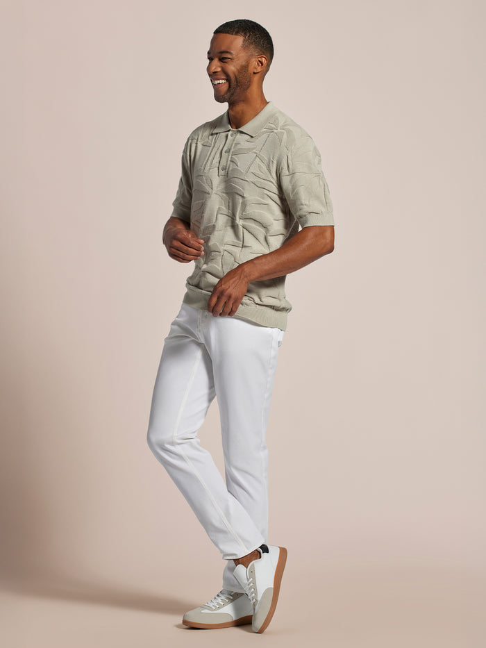Cream palm-print sweater polo, white pants, and sneakers, front view.