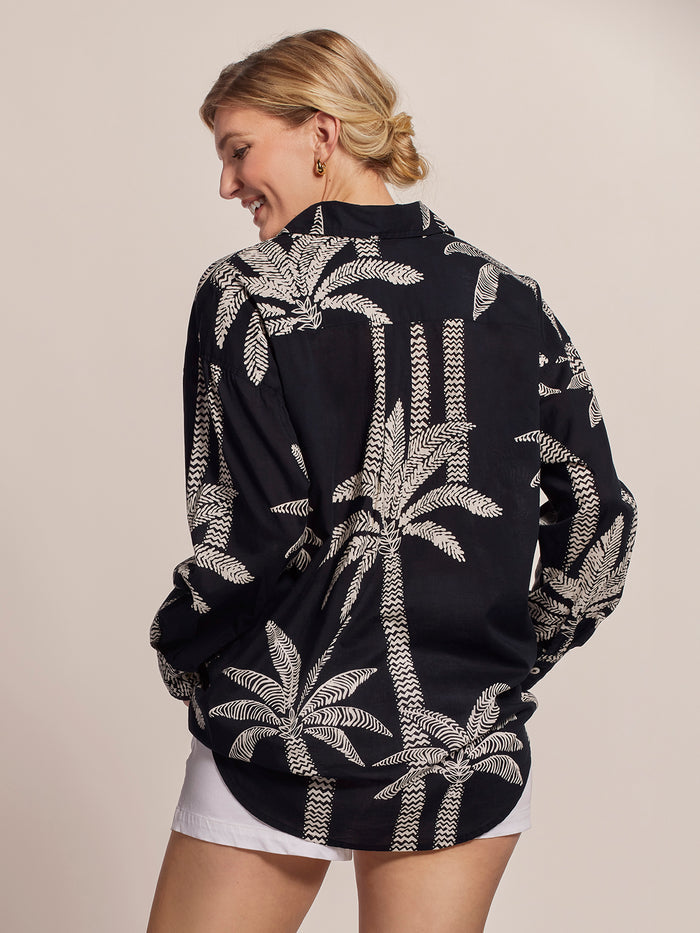 Black and white palm-print cotton voile blouse with white shorts, front view.
