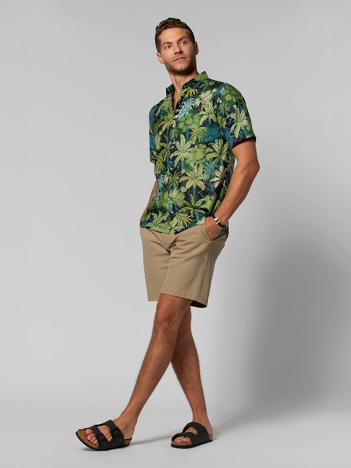 Greenish and navy-blue palm-print short-sleeve shirt, tan shorts, black sandals, front view.