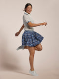 White pointelle knit short-sleeve polo and blue floral skirt, twirling front view.