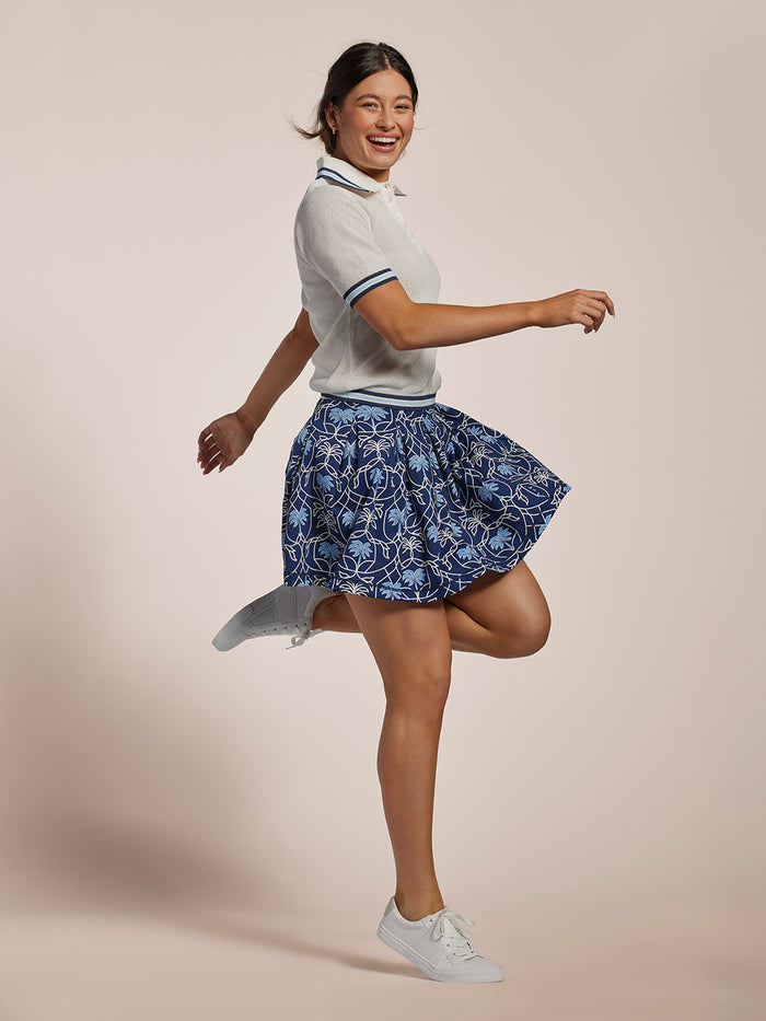 White pointelle knit short-sleeve polo and blue floral skirt, twirling front view.