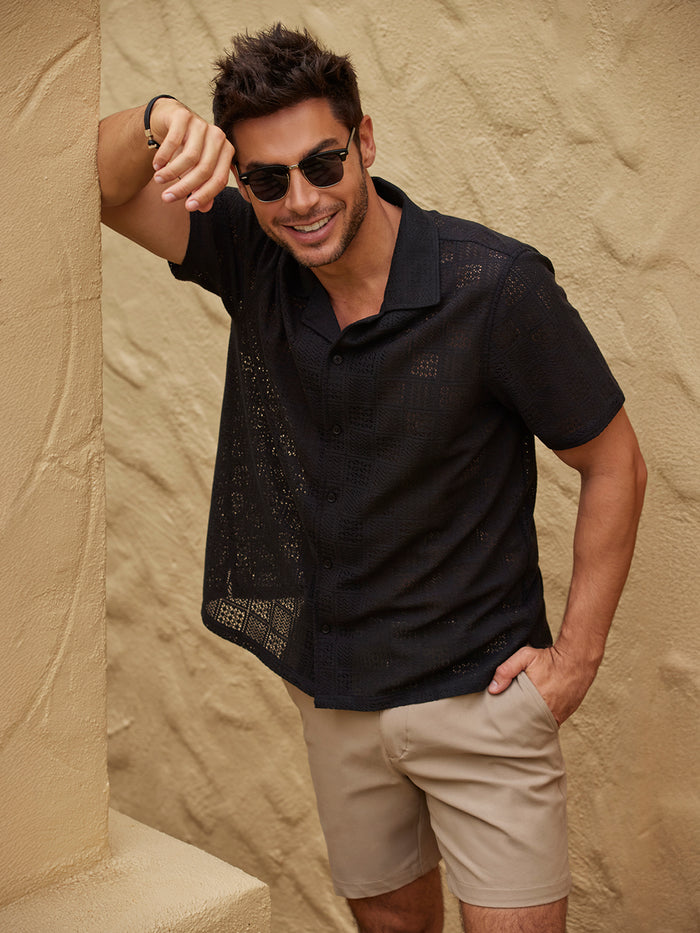 Black tropical floral short-sleeve shirt and tan shorts, front view with man smiling.