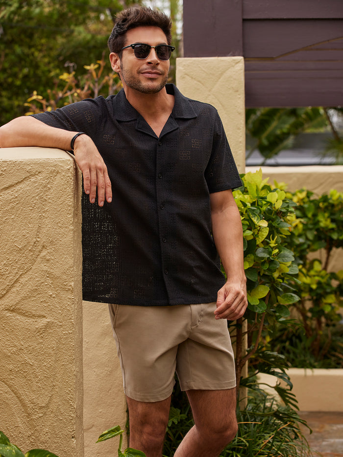 Black cabana shorts, worn by man, side view by beige breeze block wall.