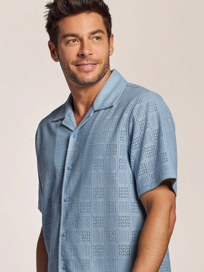 Light blue breeze block-print cabana shirt; side view of man looking left and smiling.