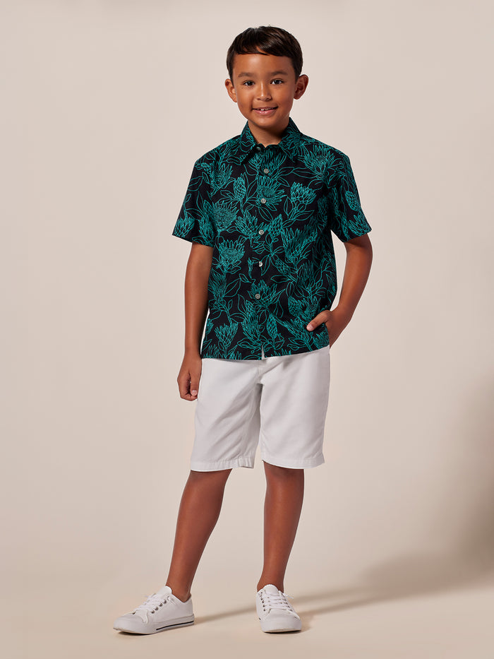 Teal floral-print short-sleeve boys shirt, front view, paired with white shorts.