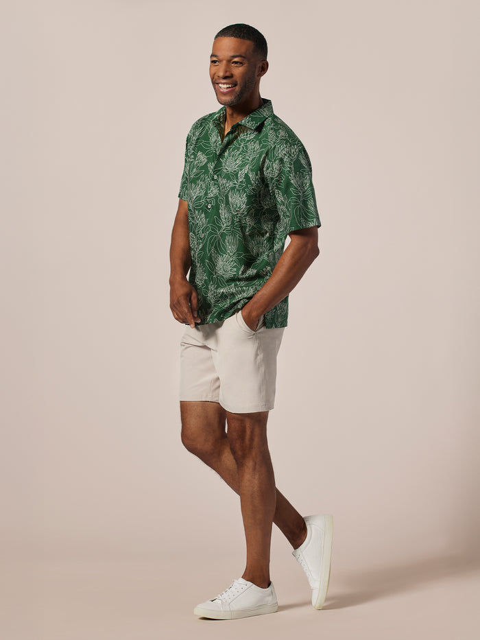 Green Protea-print short-sleeve shirt, beige shorts, and white sneakers, full front view.