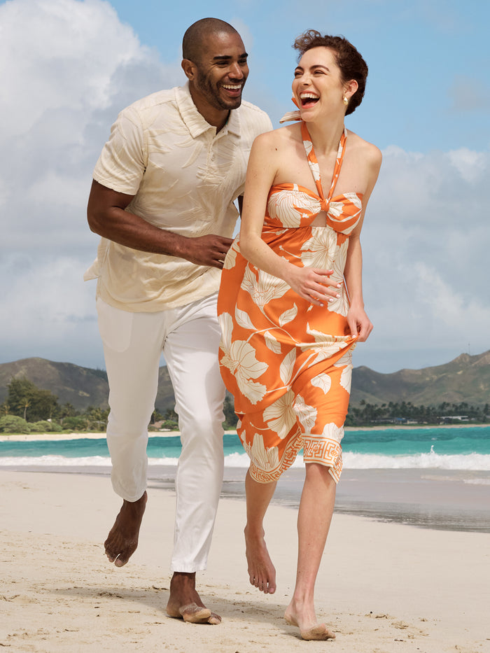 Red and yellow hibiscus-print sleeveless dress, beachside view.