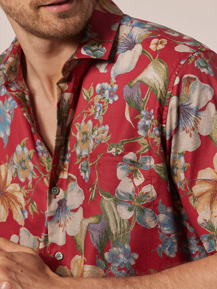 Red floral-print cotton Hawaiian shirt, colorful pattern, shown from chin to chest.