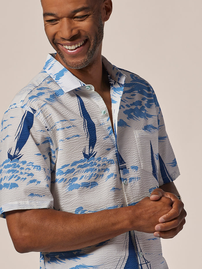 Blue and white sailboat-print short-sleeve shirt, front view, hands clasped.