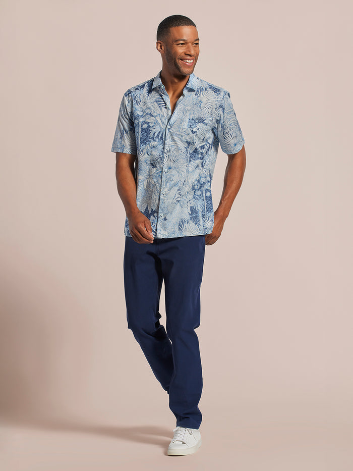 Blue floral cotton shirt, navy pants, and white sneakers, walking front view.