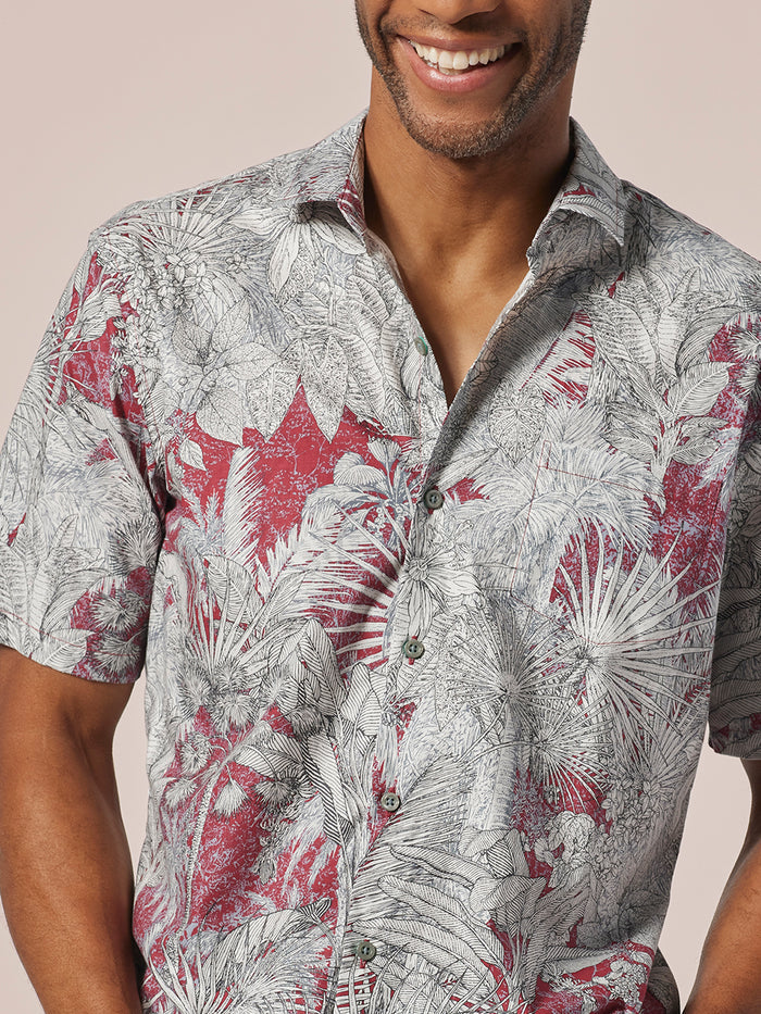 Red and white tropical leaf-print short-sleeve shirt, front view.