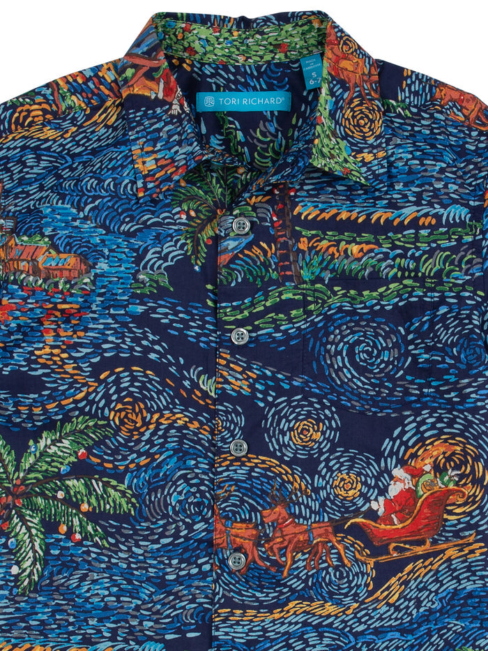 Blue shirt with colorful swirl, palm tree, house, and sleigh print, front view.