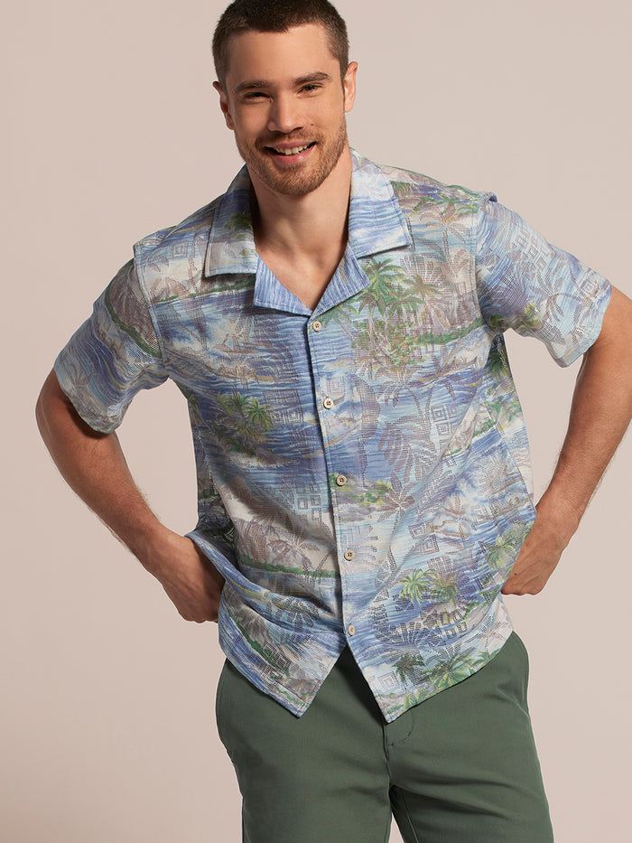 Blue and green tropical-print short-sleeve shirt with green pants, front view.