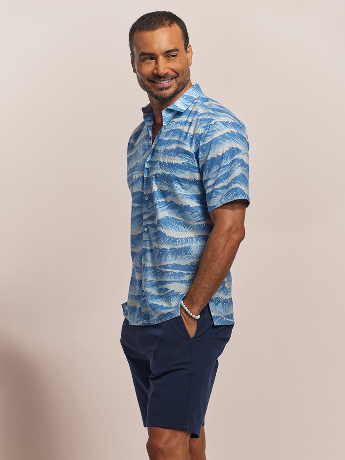 Sky Blue Ocean wave-print short-sleeve cotton shirt patterned with navy shorts, front view, model smiling.