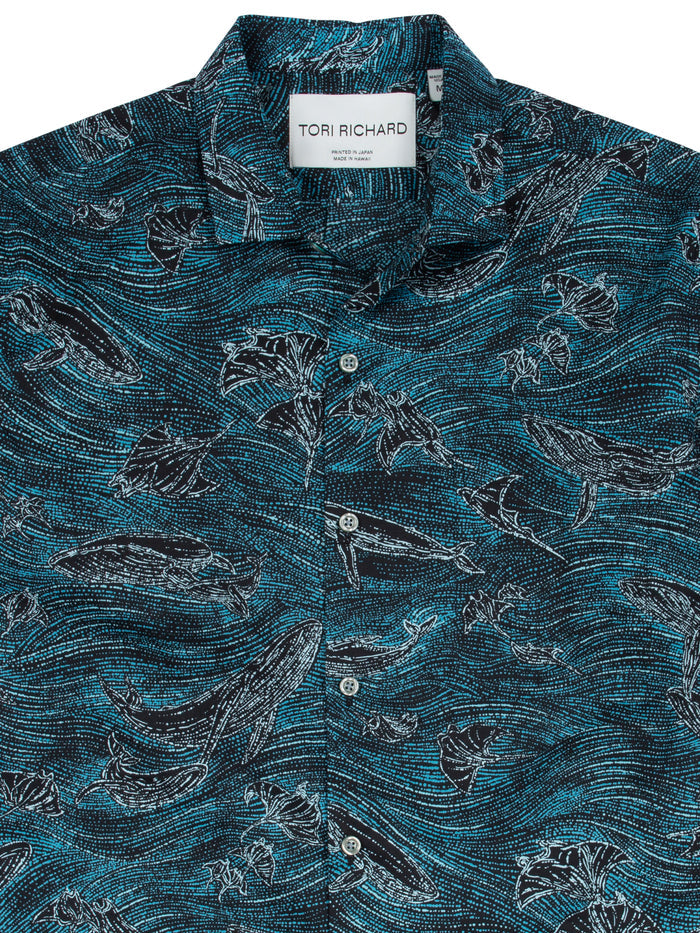 Teal and black cotton shirt with ocean dot print, whales, and glowing phytoplankton, front view.