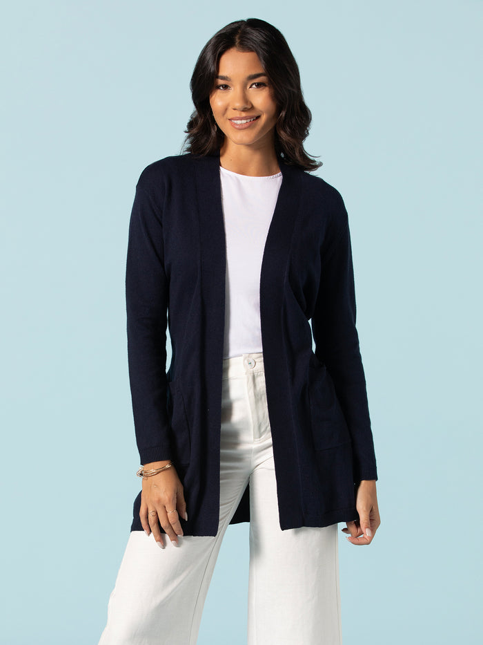Navy knit duster, open front, over white shirt and pants, front view.