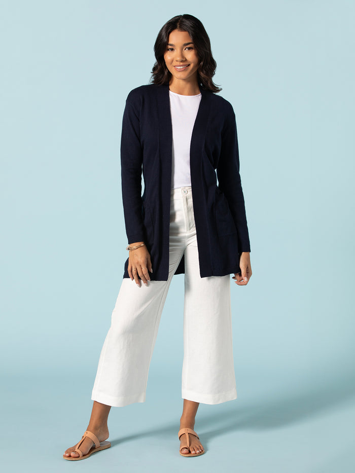 Navy knit duster, white shirt, and ivory wide-leg pants, front view on light blue backdrop.