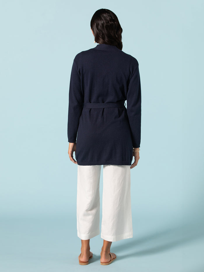 Navy open-knit duster, white wide-leg pants, and sandals, full front view.