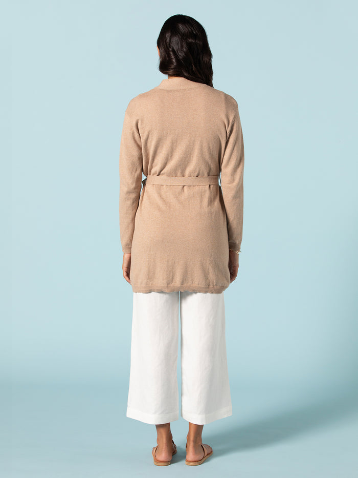 Beige knit duster, white wide-leg pants, tan sandals, full front view.