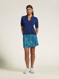 Blue sweater, retro-pattern skirt, white sneakers, front view, hands in pockets.