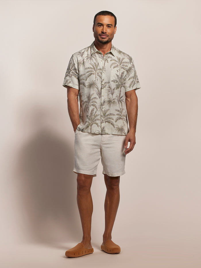 Multicolor palm print short-sleeve shirt, beige shorts, tan slip-ons, full front view in both images.
