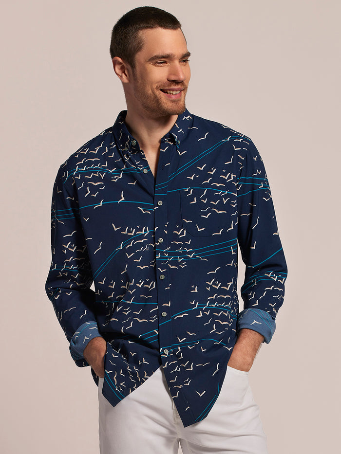Navy shirt with white bird and blue stripe print, button-up, long sleeves front view, man smiling .