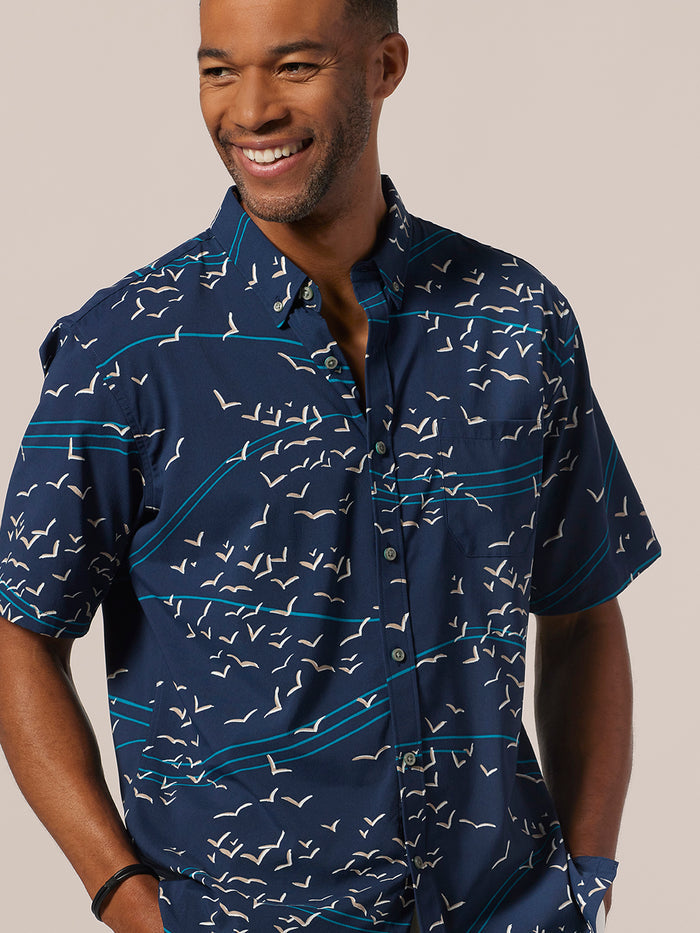 Light blue, moisture-wicking shirt with white bird pattern, front view, hands in pockets.