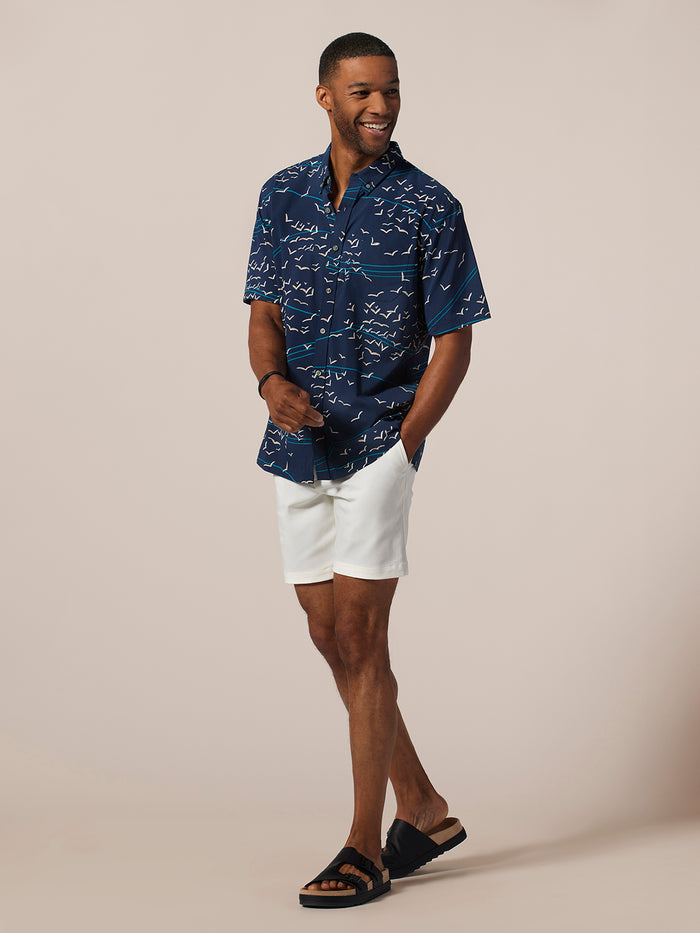 Light blue short-sleeve Sora Tradewind shirt and white shorts, front view, hand in pocket.