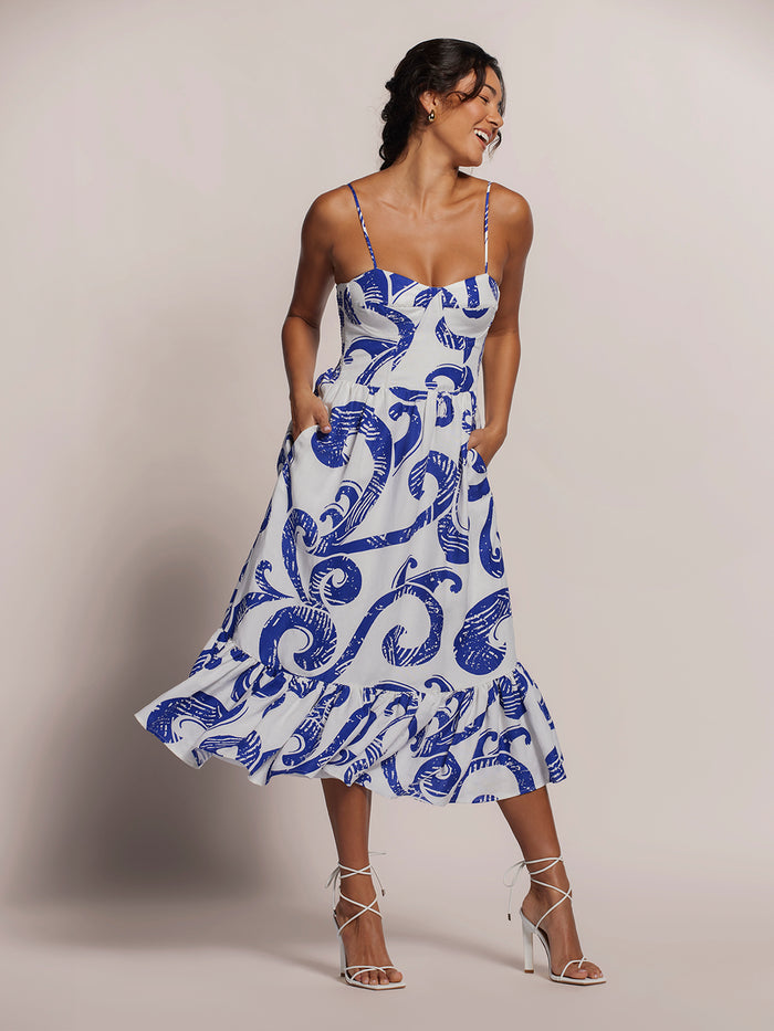 Blue swirl-print sleeveless dress with fitted corset bodice, hands in pockets, front view (Images 1 & 2).