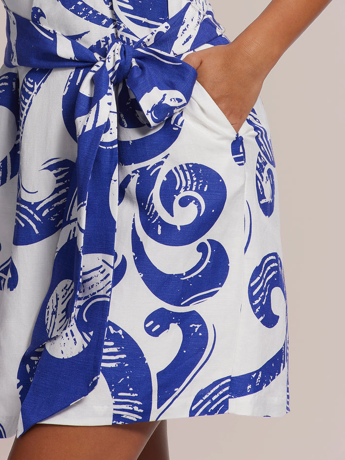 Blue swirl-print Indiana dress, person standing with one hand in pocket, front view.