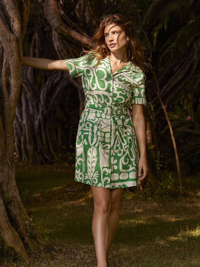 Green floral-print Magda dress, outdoor view by a tree in lush greenery.