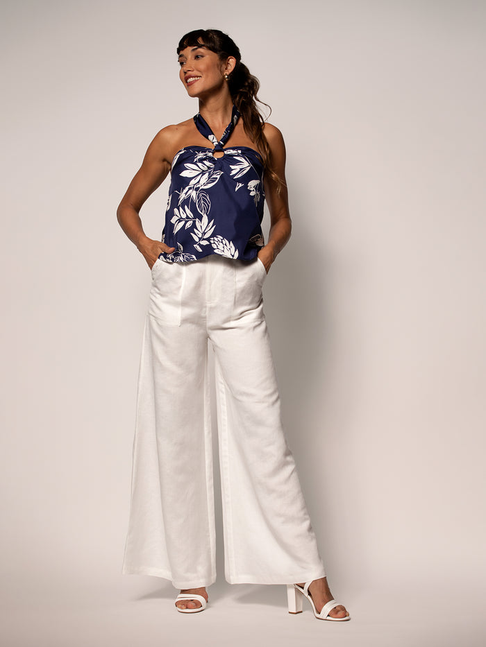Navy floral halter top with wide-leg white pants and heels, shown from front.