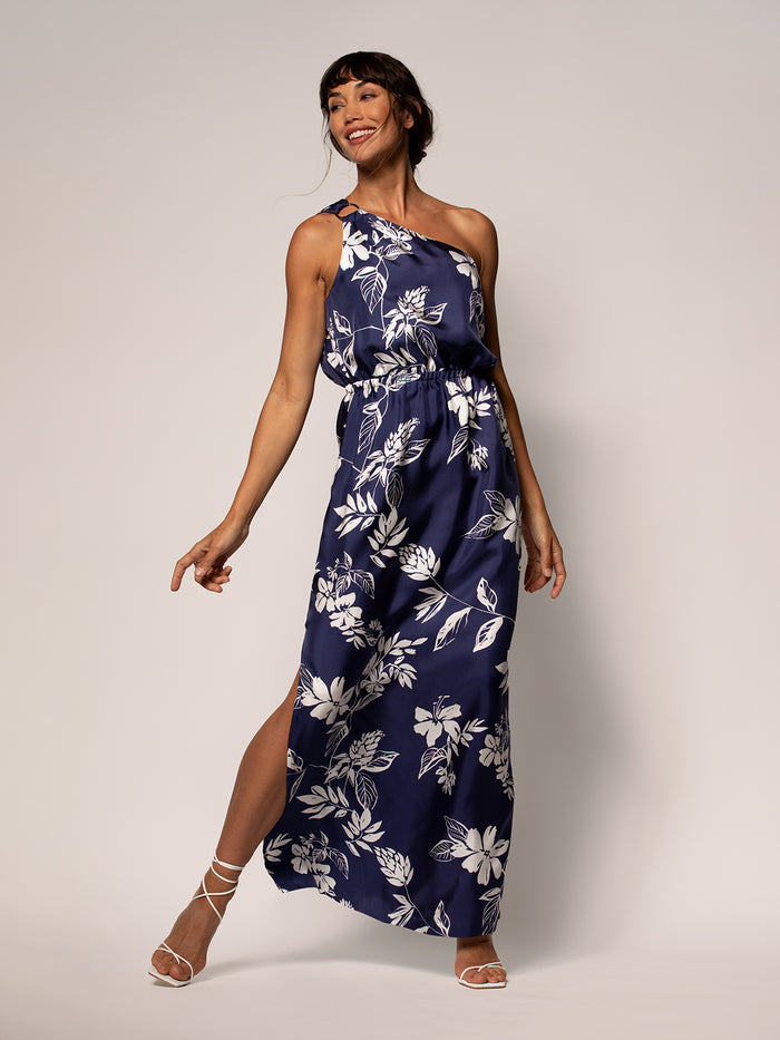 Navy and white floral Presley dress, front view; woman smiling, one arm bent, one leg forward.