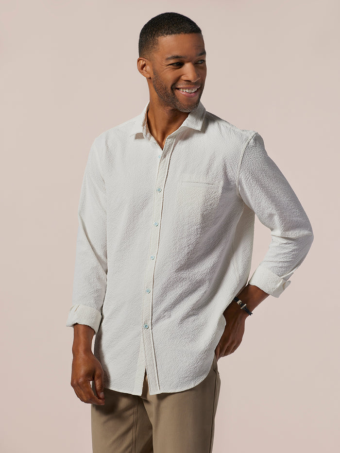 White solid long-sleeve shirt with chest pocket, worn by man with tan pants, front view shown in both images.