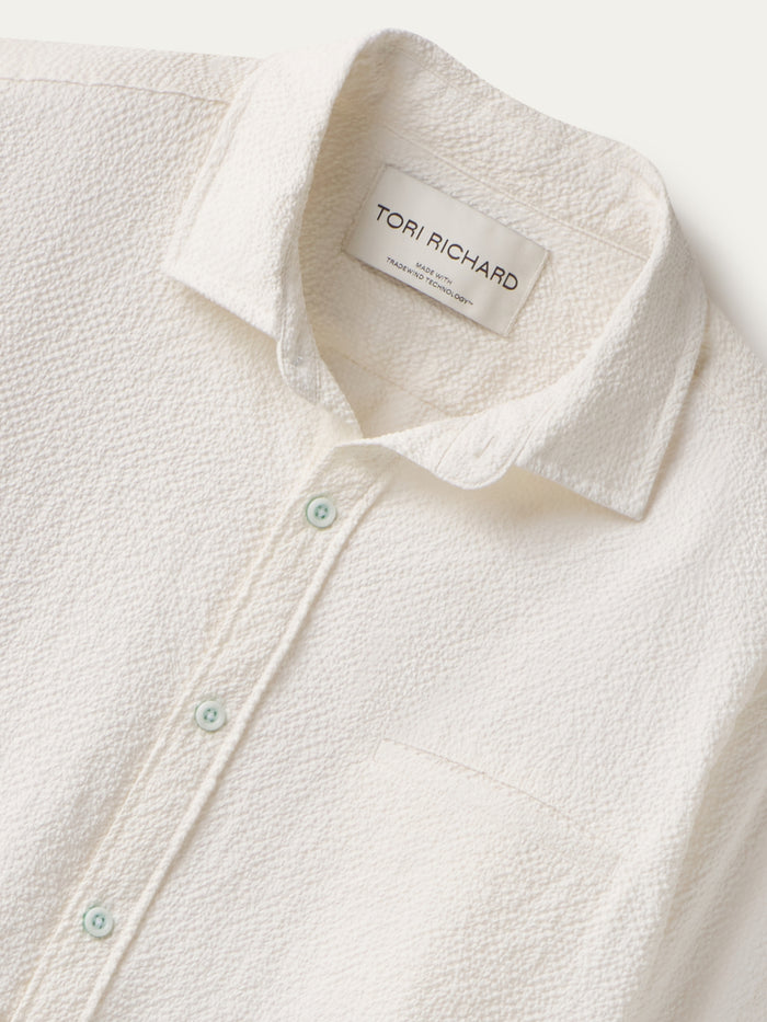 White solid long-sleeve button-up shirt, front view with collar and chest pocket shown in closed up.