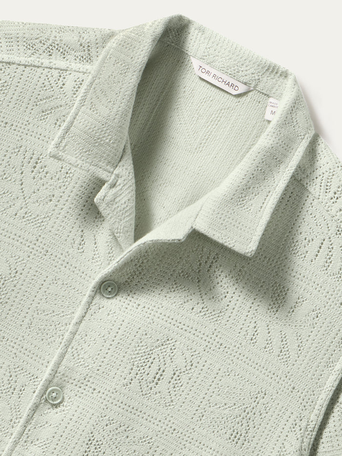 Light green textured button-up shirt with collar, top-down view.