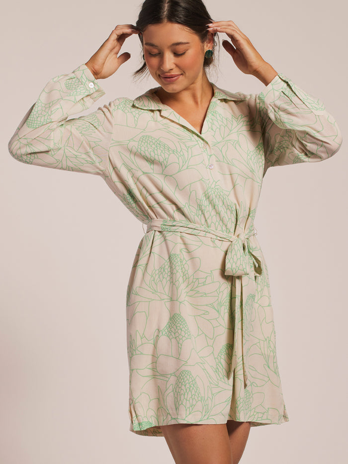 Cream and green floral-print wrap dress with sash belt, front view, model touching hair.