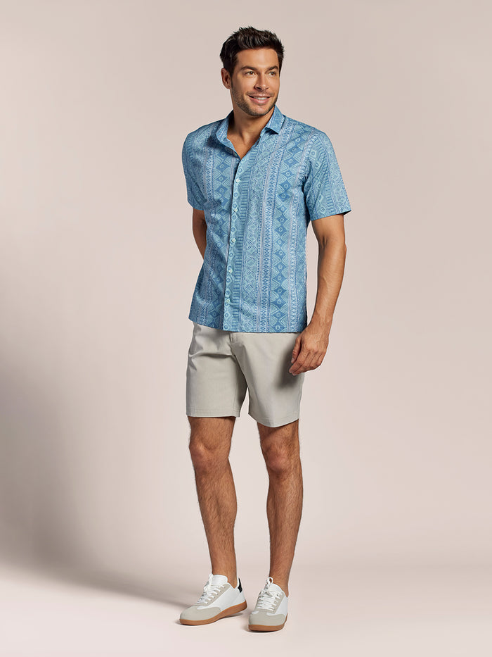 Blue Tori Tapa print button-up shirt, gray shorts, and white sneakers, standing front view.