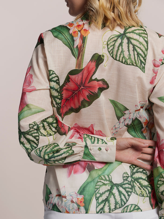 Green and red leaf-print top, rear view, model’s hands behind back.
