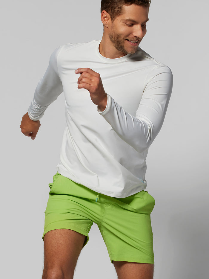 White shirt and bright green solid swim trunks, side view highlighting Tradewind Technology details.
