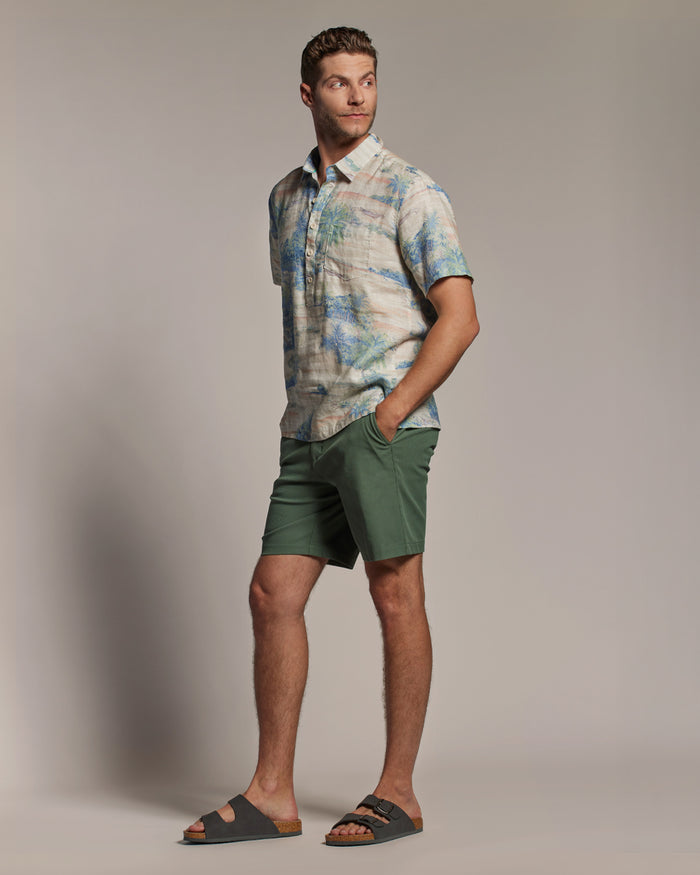 Light blue slub linen half-placket shirt and green shorts, side view, hands in pockets.