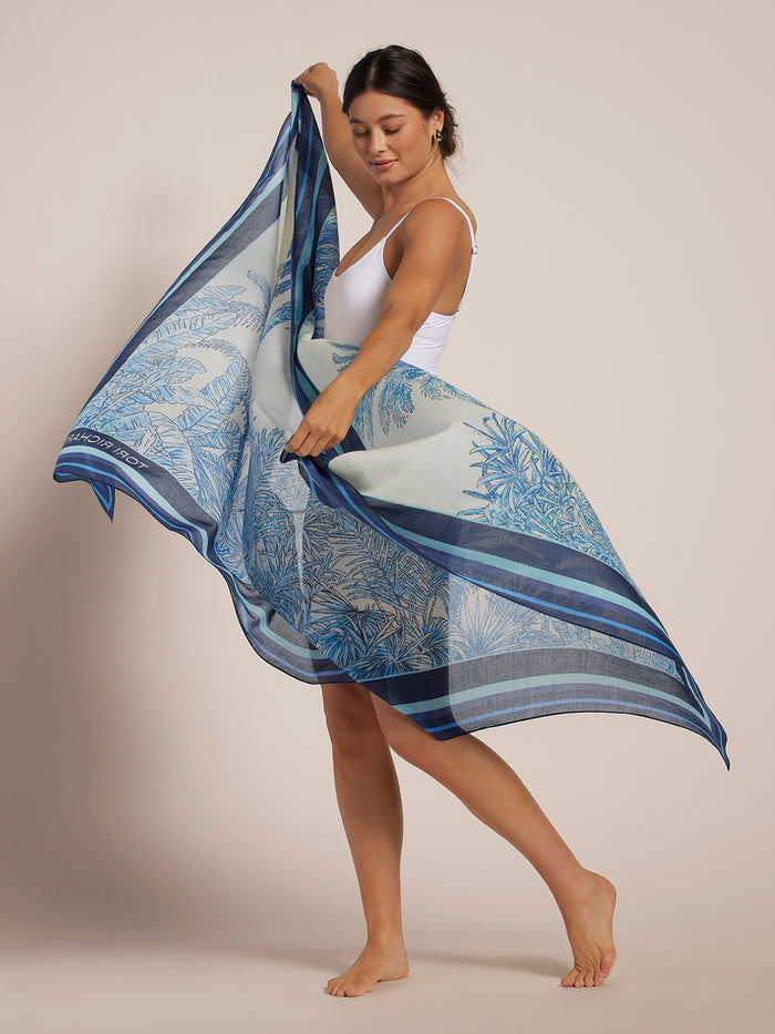 Blue and white tree-print pareo sarong tied at waist, side view, worn over white bodysuit.